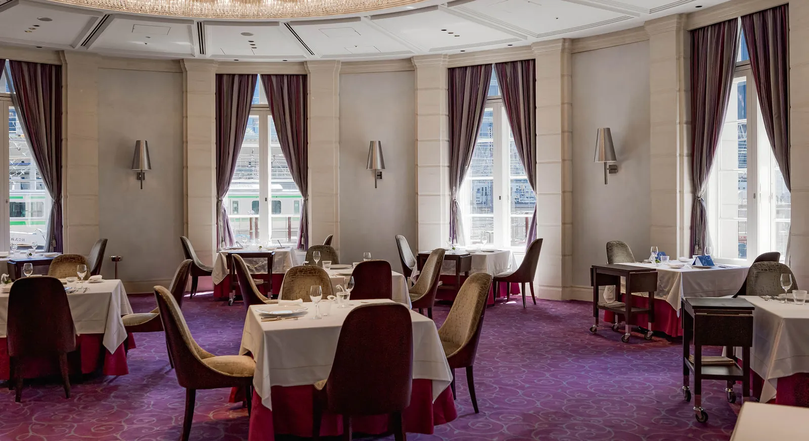 The Blanc Rouge dining room: tables laid in white, plum carpet and curtains and tall windows.