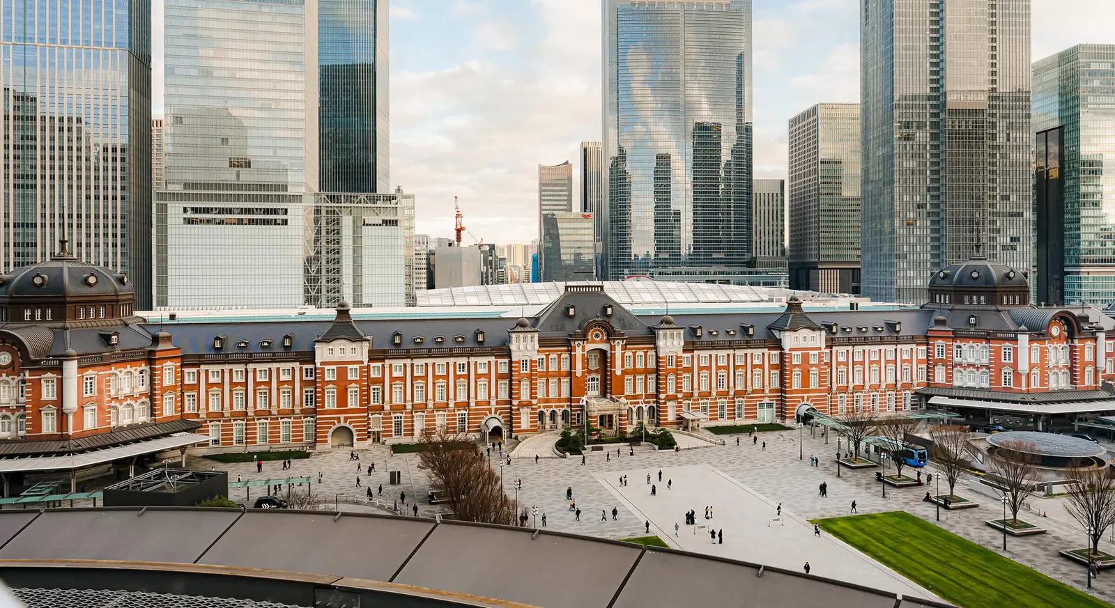 The red-brick façade of the station seen from above by day, with the Marunouchi square in front and the towers behind.