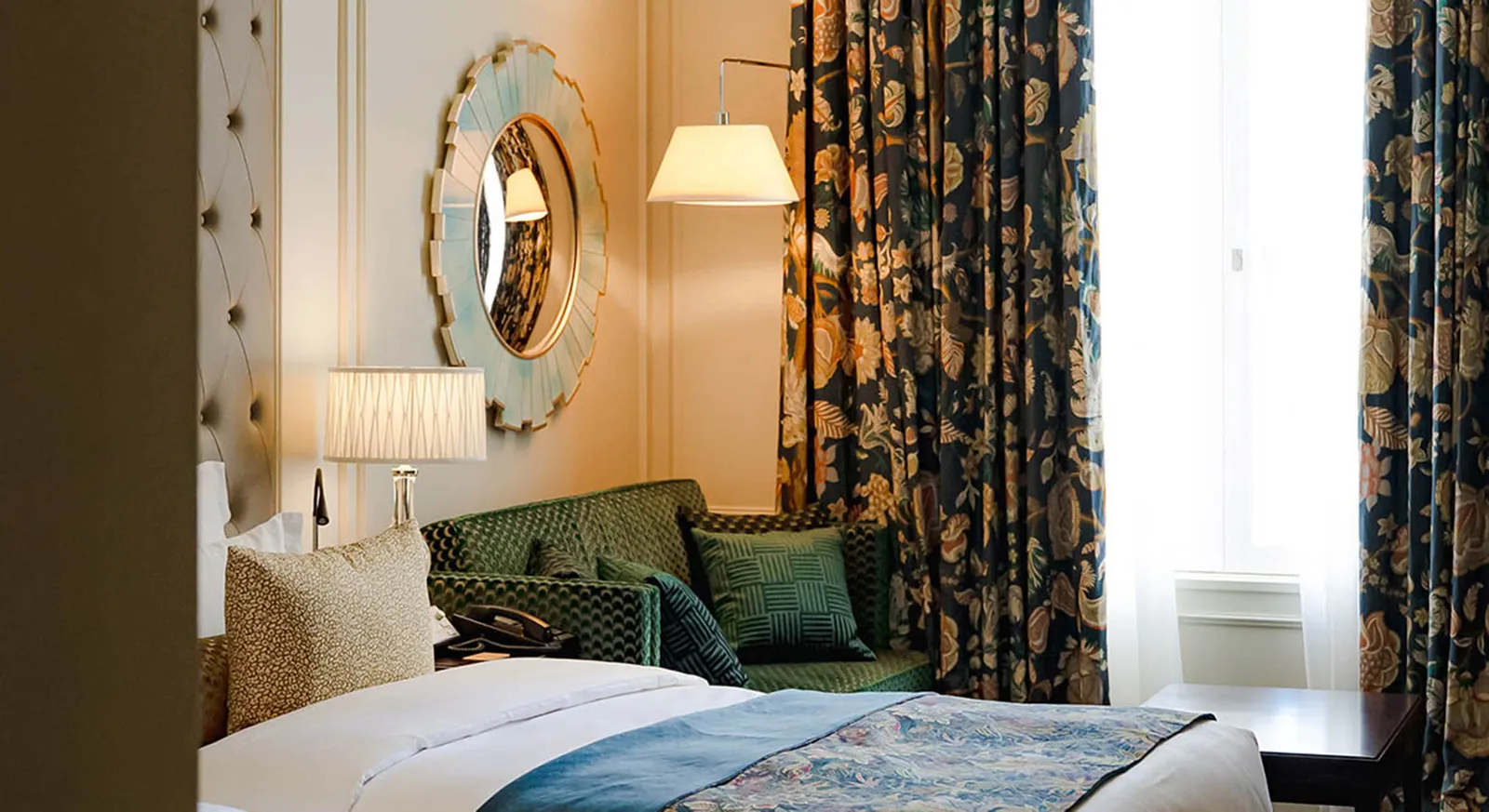 The Liberty room Jade: the bed, the green sofa, Liberty’s floral curtains and the sunburst mirror.