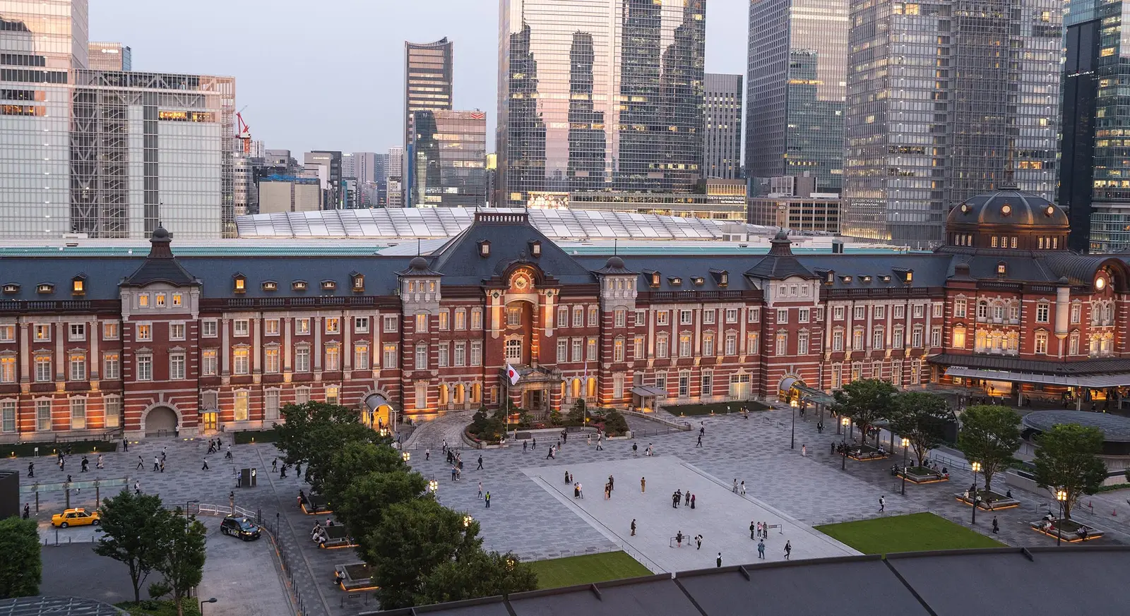 The station’s façade from above at dusk, with its windows lit, the Marunouchi square and the towers around it.