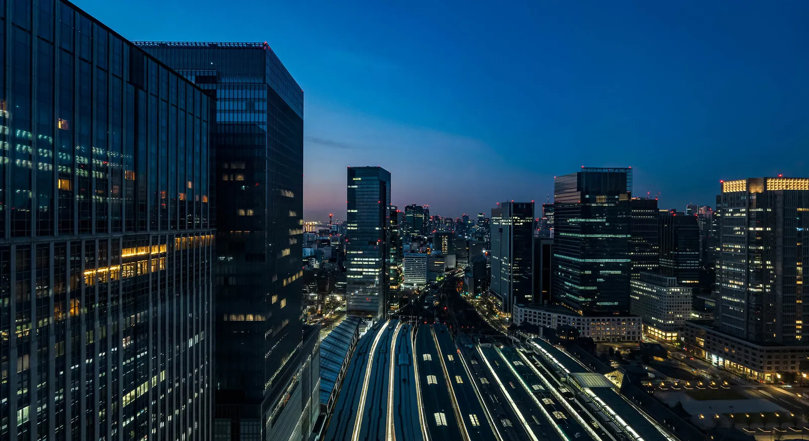 Tokyo Station’s tracks at night, seen from above between the lit towers.