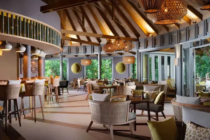 Onu’s dining room under its bamboo roof, with wicker lamps and windows onto the garden.