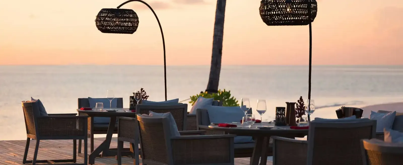 Vakku’s tables on the beach, laid at sunset under woven lamps.