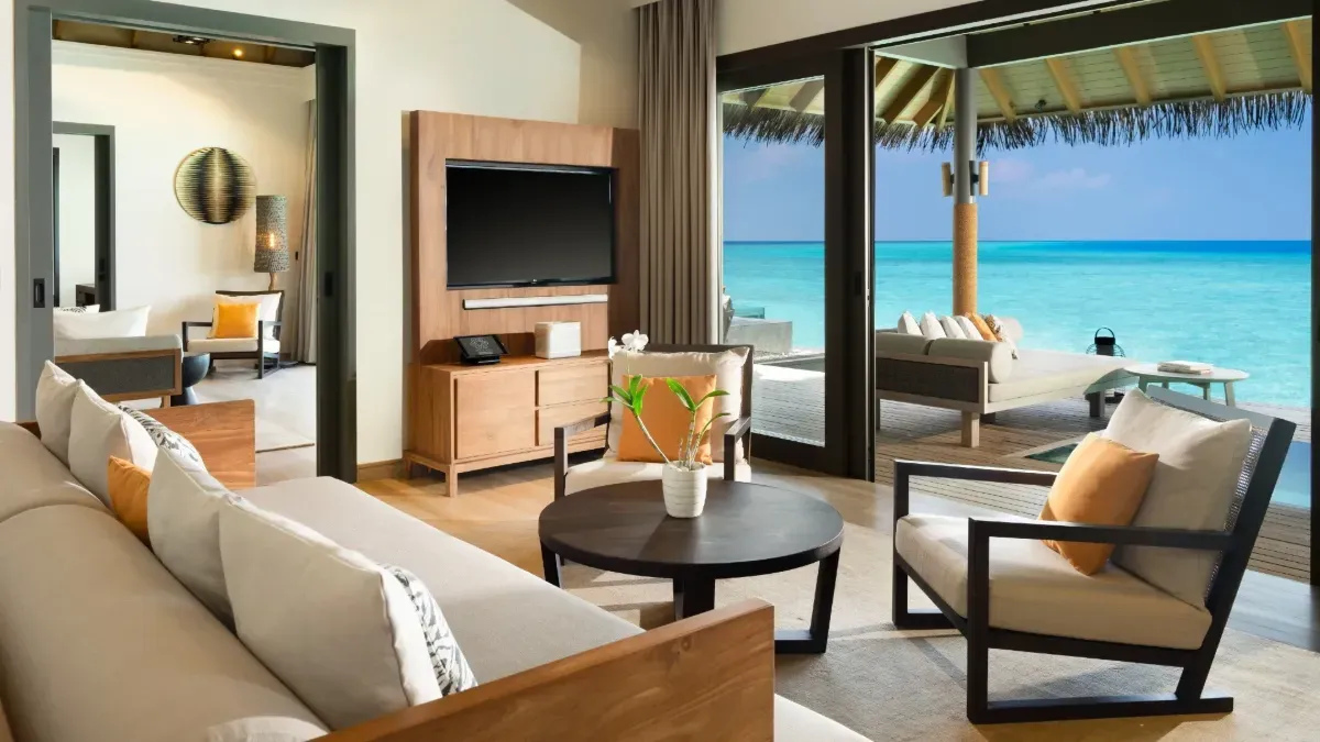 The living room of a One Bedroom Overwater Pool Residence, open to the deck and the sea.
