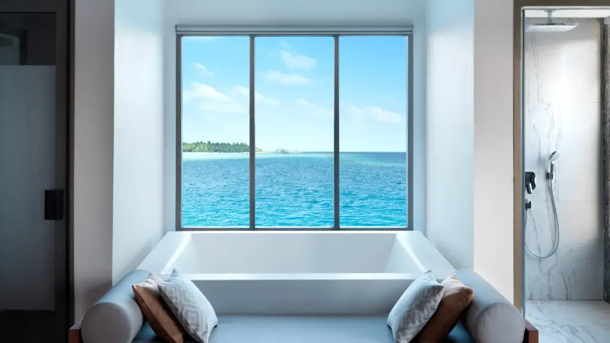 The bathtub of The Vakkaru Overwater Residence, under a window onto the open sea.