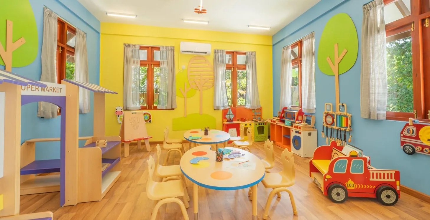 The room at On The Move, the children’s club, with small tables, wooden play houses and a toy fire engine.
