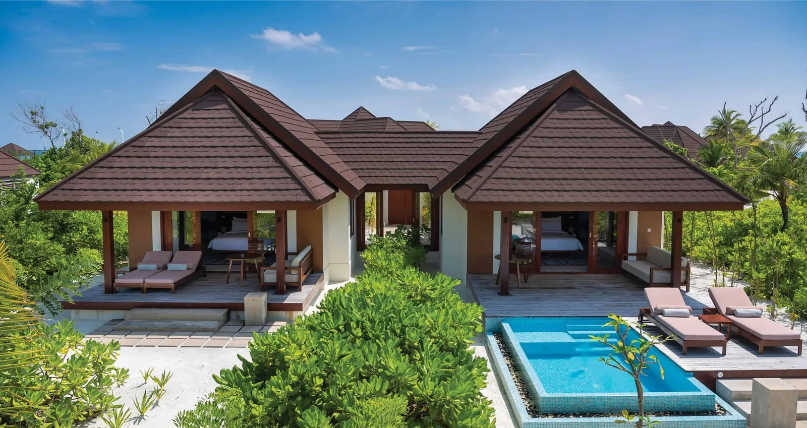 The twin villas of the Two Bedroom Beach Villa with Pool, with the pool and loungers in the garden.