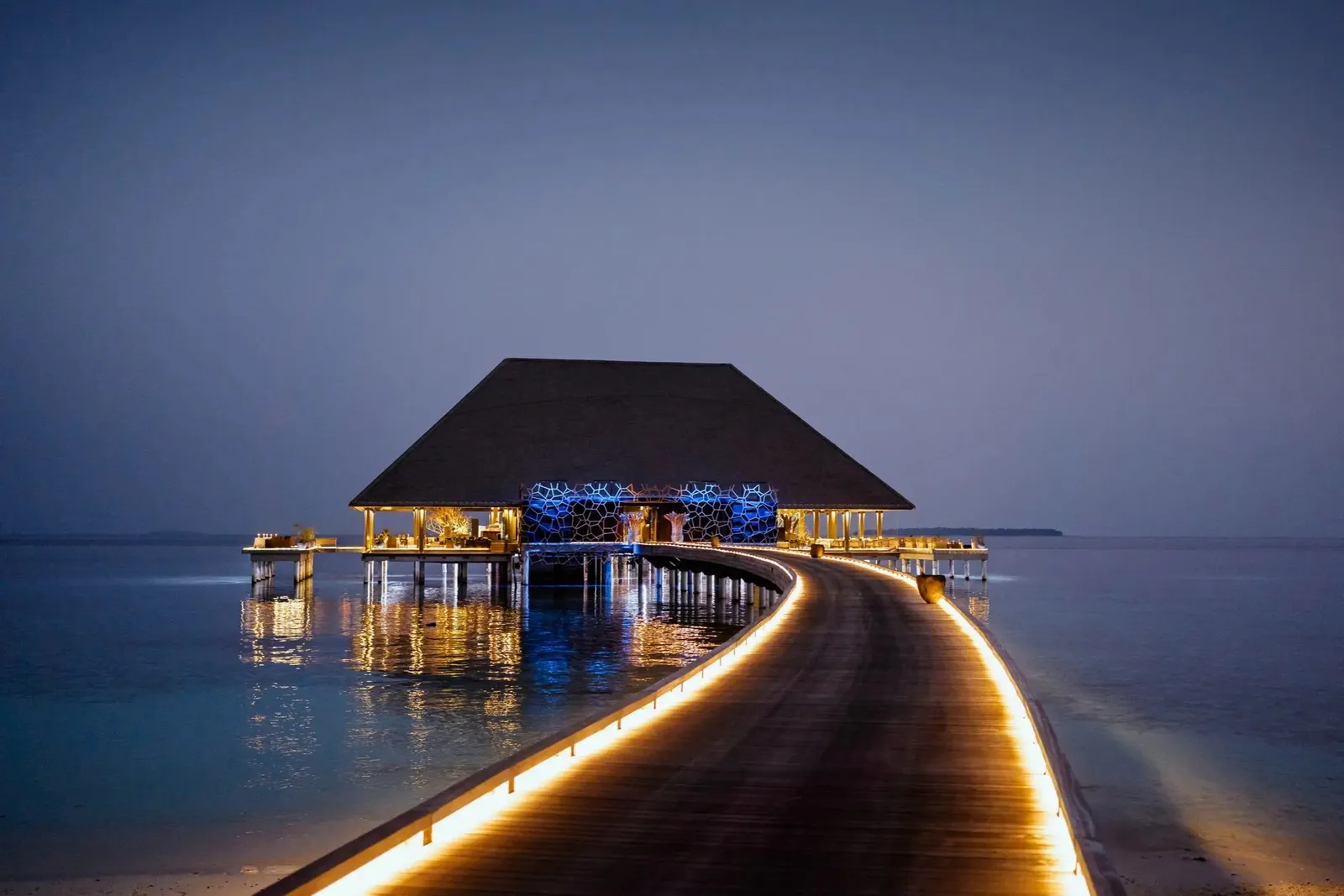 Aragu over the water at dusk, the lit walkway leading to it