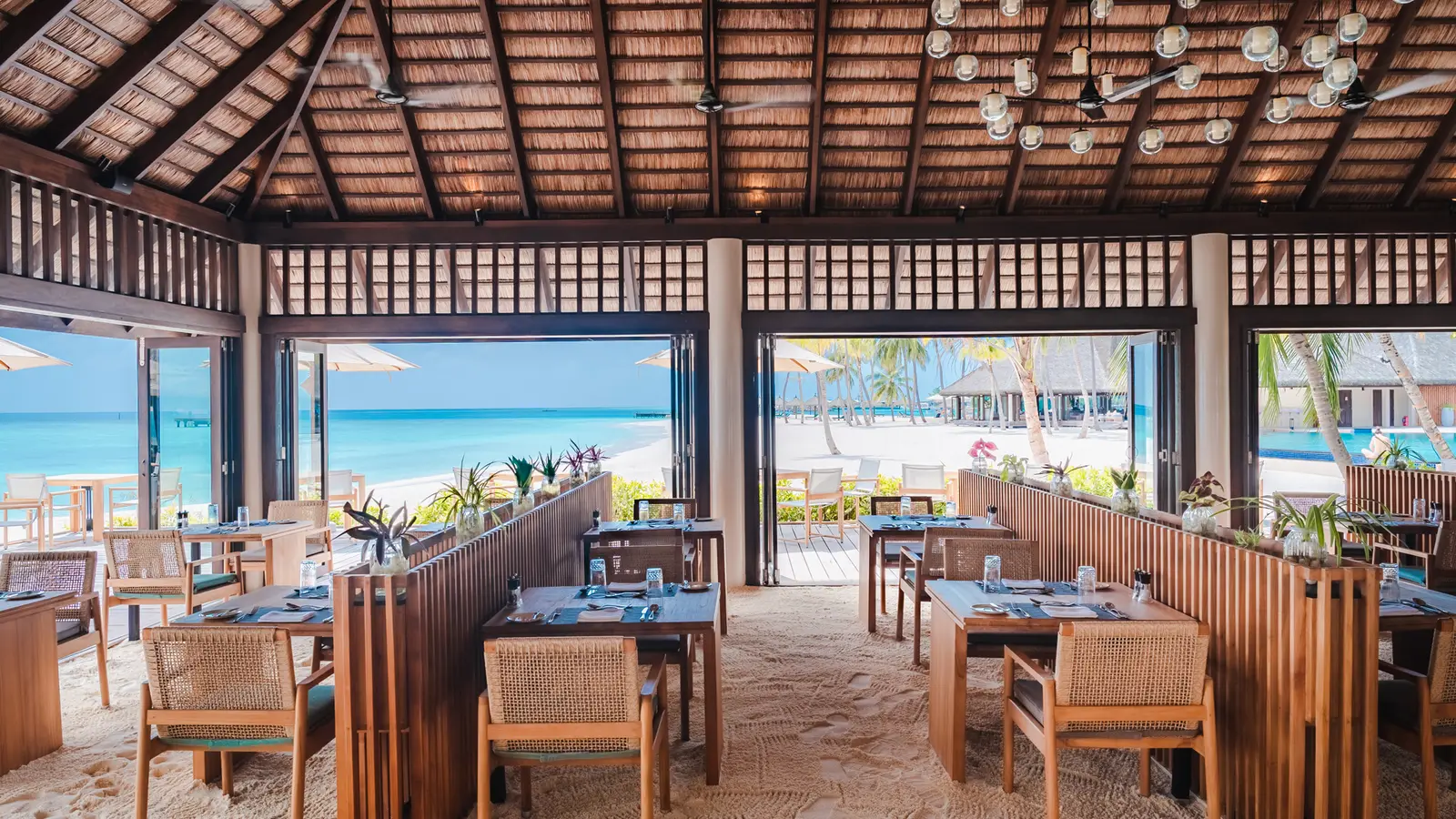 The Dhonveli dining room, with its sand floor and the sea beyond the glass.