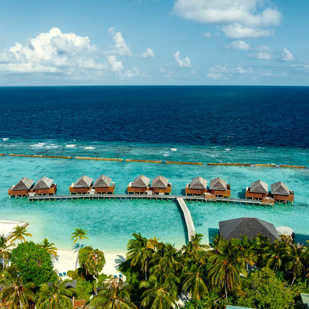 The island from above, with the row of overwater villas and the reef.