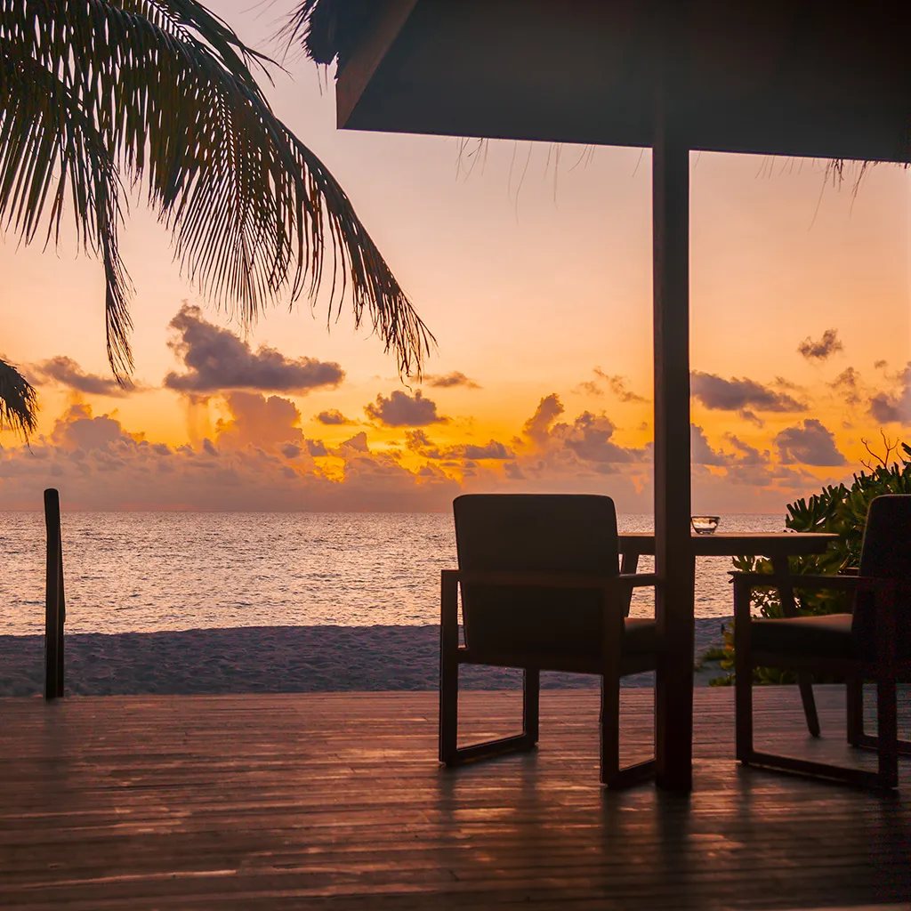 The porch of a Sunset Jacuzzi Beach Villa at sunset, open to the sea.