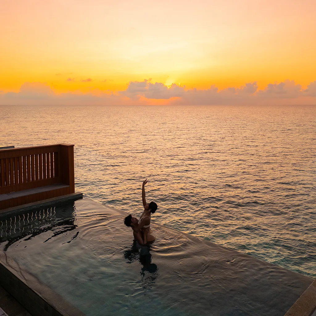 Someone in the infinity pool of a Sunset Ocean Pool Villa at sunset.