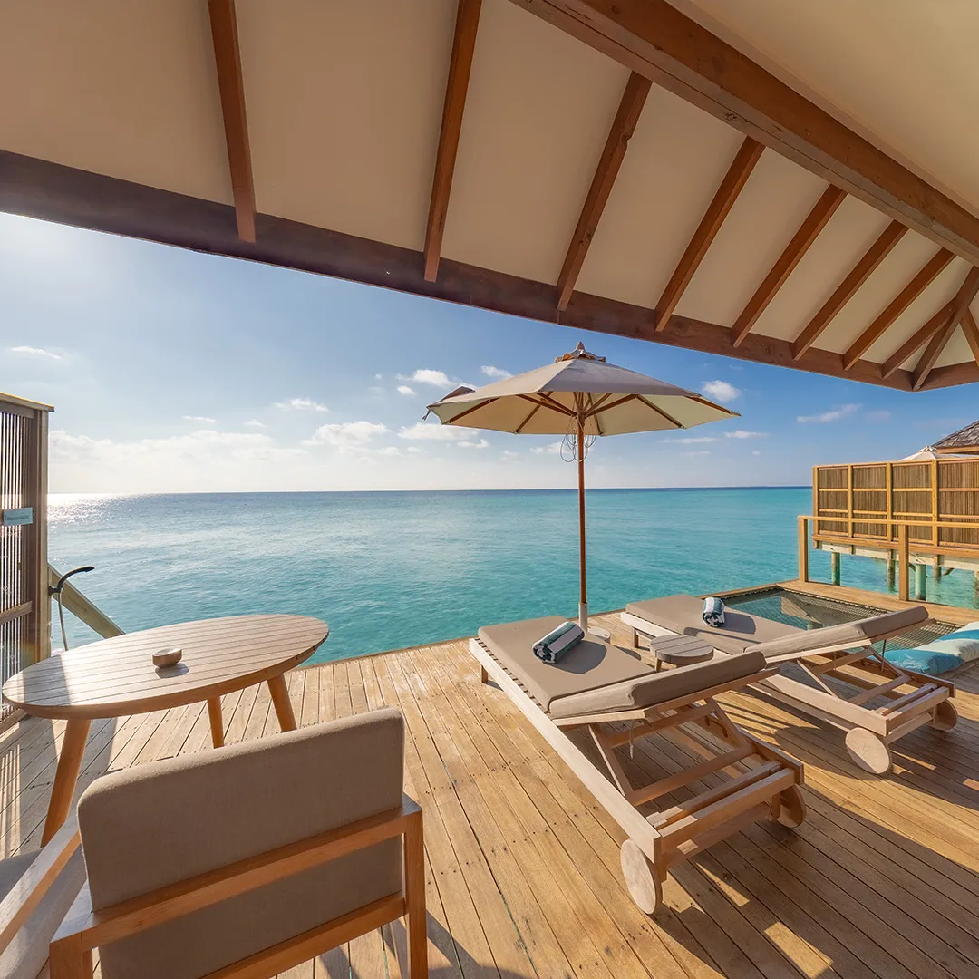 A Sunset Ocean Villa deck, with loungers and a parasol over the sea.