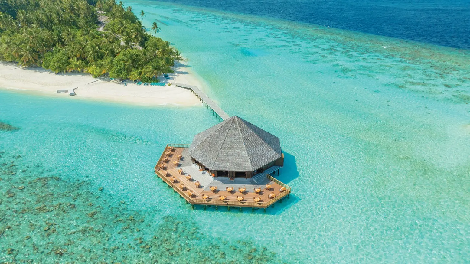 A pavilion with a pointed roof out in the lagoon, joined to the beach by a walkway.