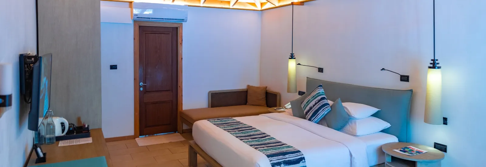 An Adjacent Beachfront Villa: the king bed, the sofa, the television and the timber front door.