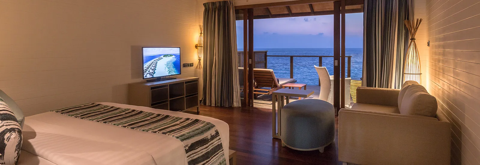 A Romantic Ocean Villa: the bed, the sitting area and the glass doors open onto the deck above the sea.