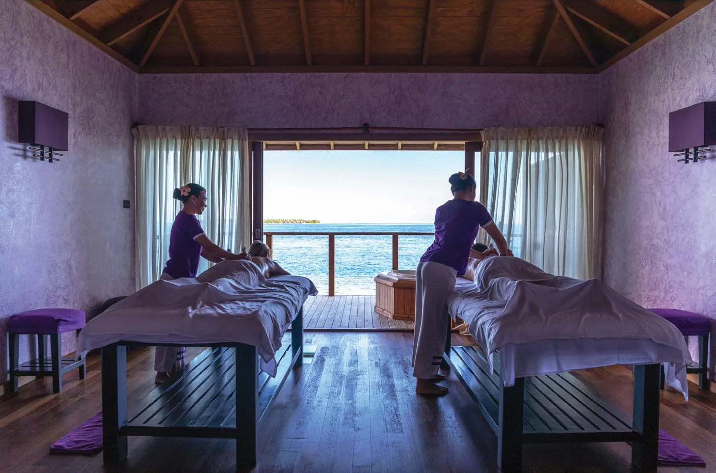 2 massages in a spa room, its glass doors open onto a deck above the sea.