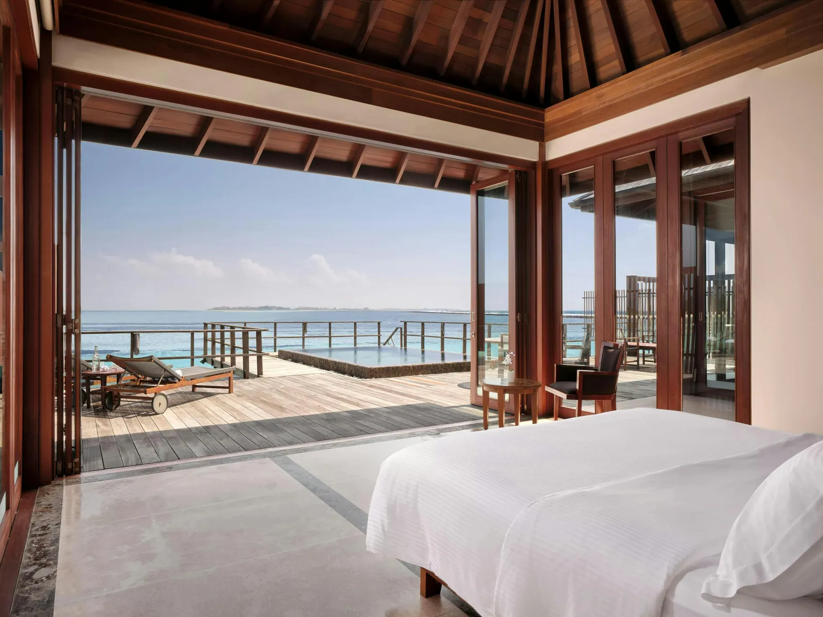 The bedroom of a One-bedroom Ocean Suite with Pool, open to the deck and the sea.