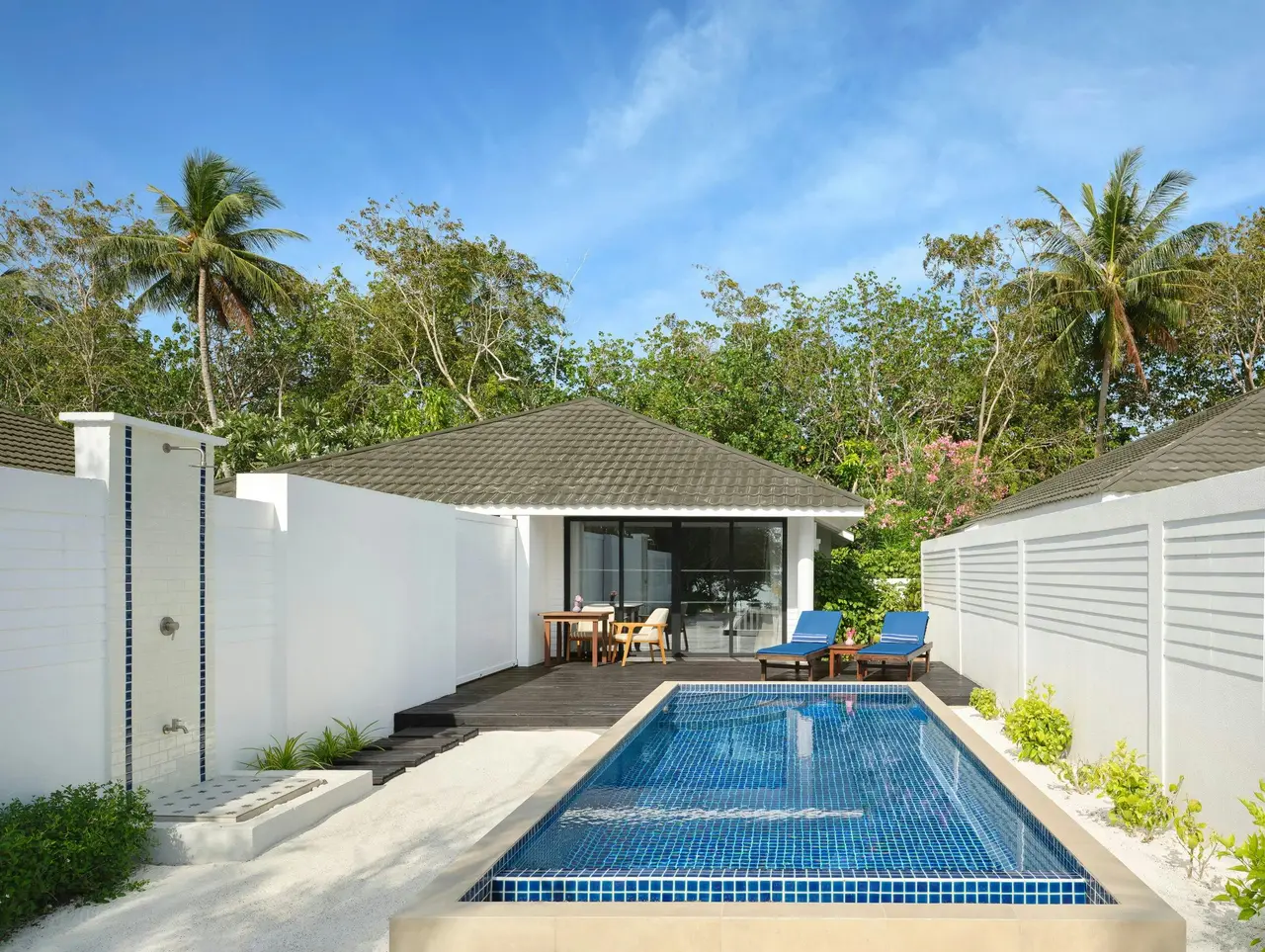 A Sunset Deluxe Beach Pool Villa’s pool in front of the house, between the garden’s white walls.