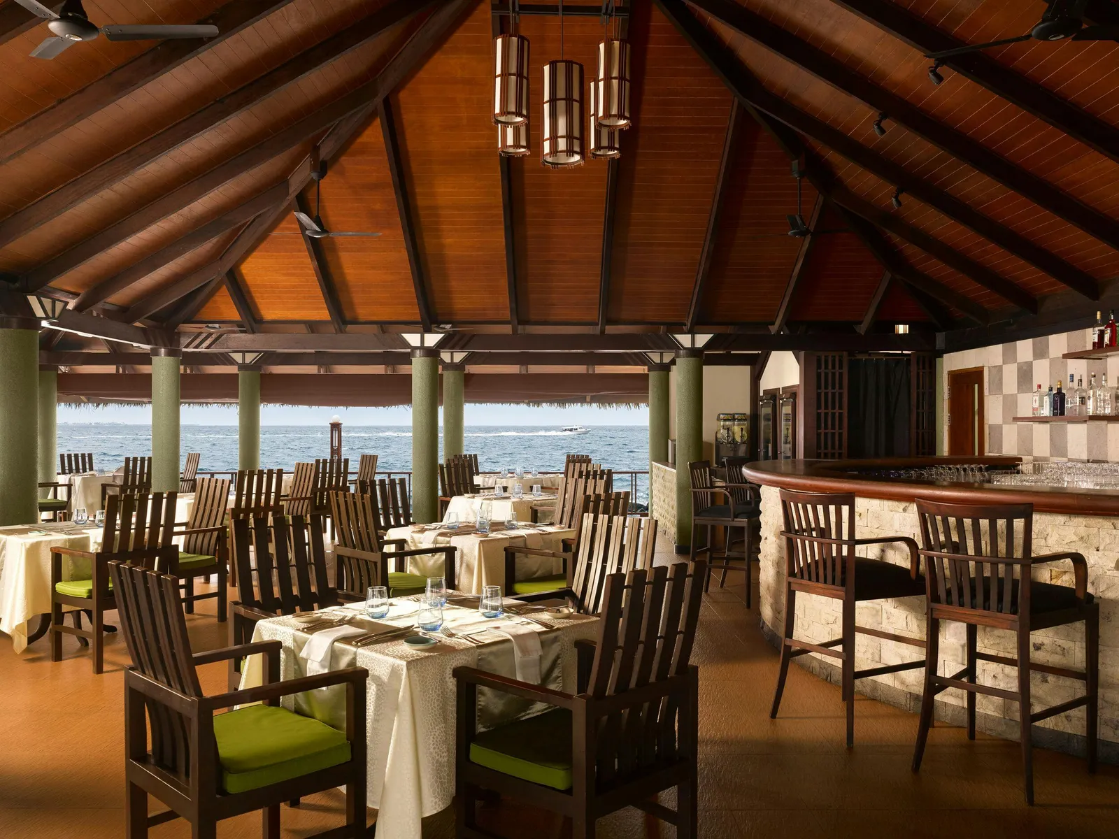 Ristorante al Tramonto under its wooden roof, tables laid and the sea beyond the columns.