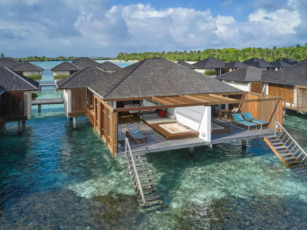 A water villa from above, its deck, loungers and steps down into the lagoon.