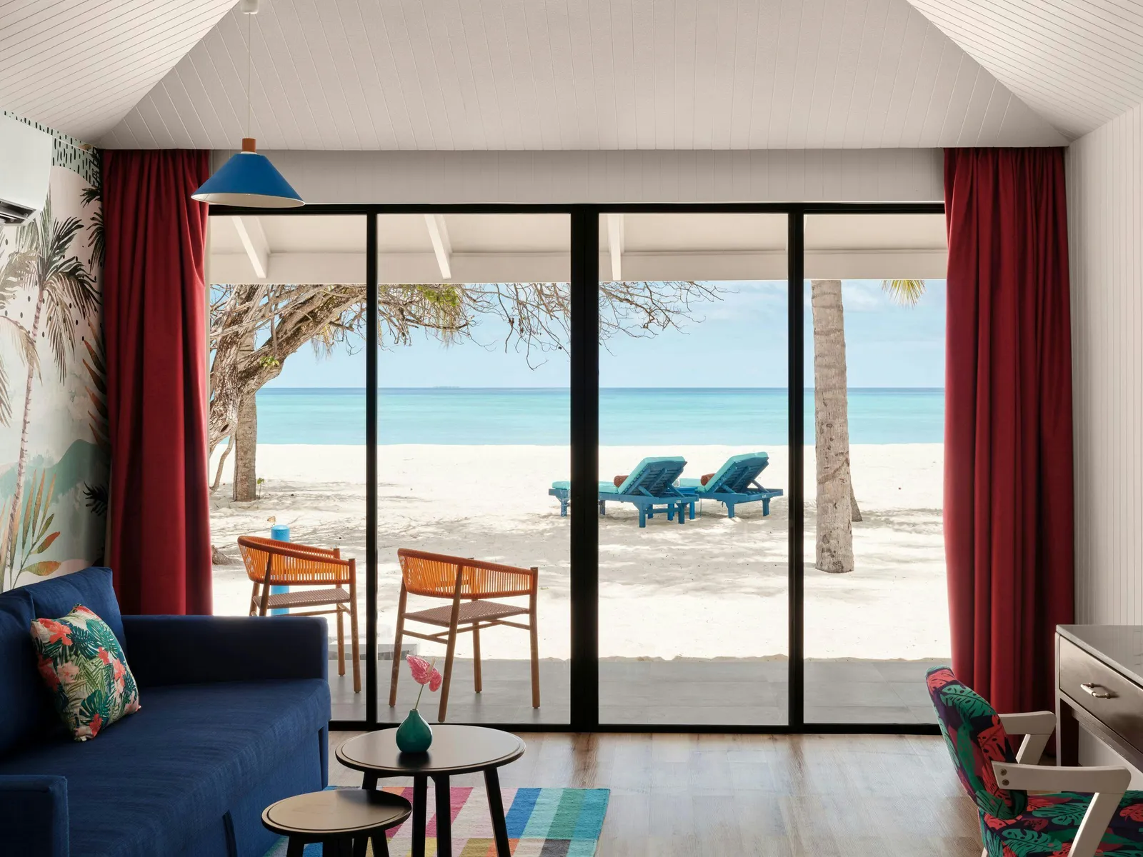Lagoon Beach Villa — Sofa and open beach-facing glazed doors, loungers outside.