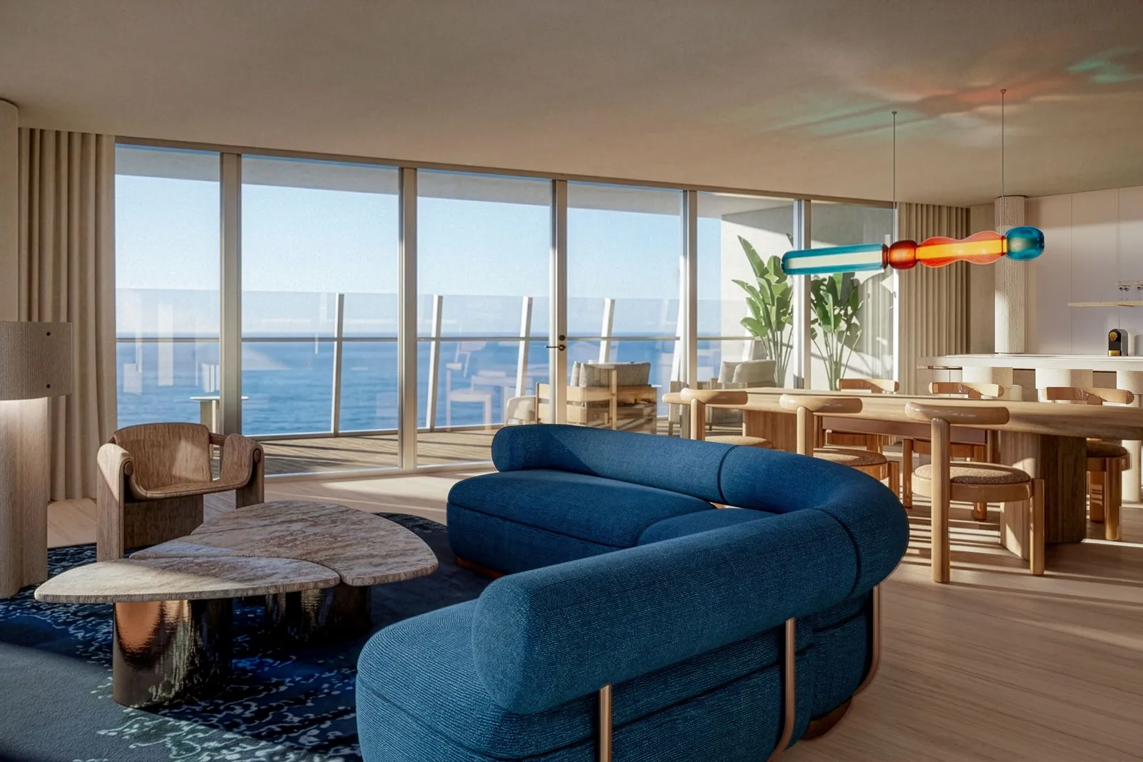 The sitting room with a curved navy sofa, the kitchen and the window on the sea