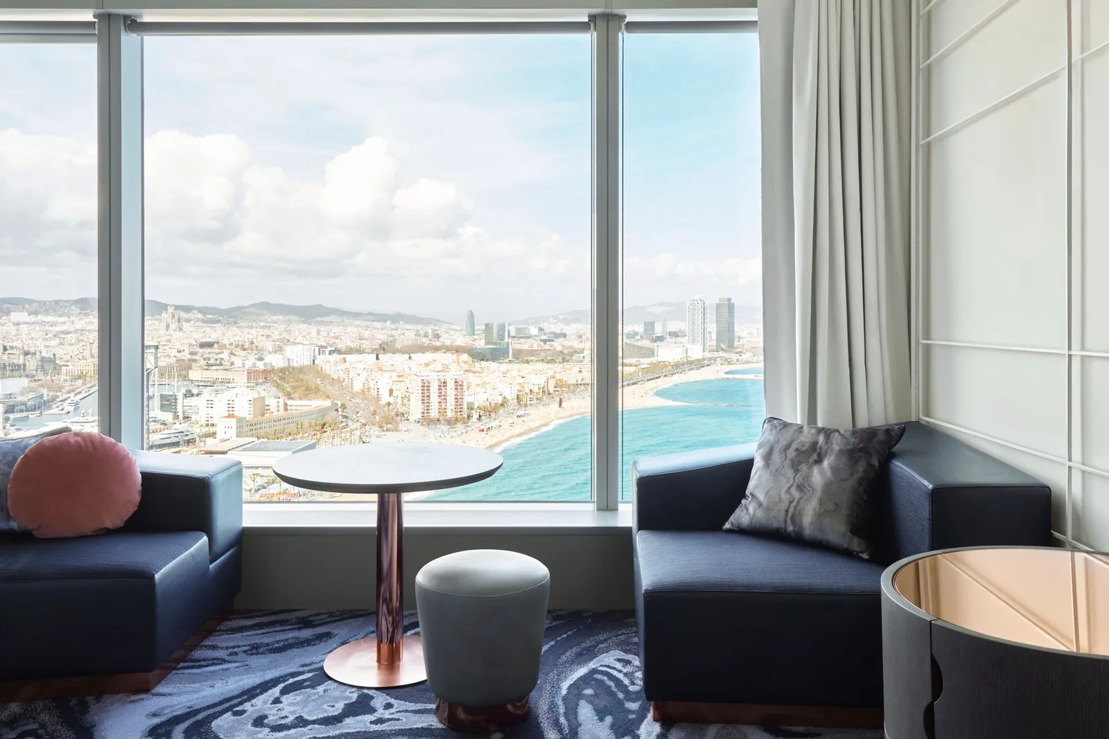 A sitting corner with 2 navy armchairs and the city and beach seen from high up