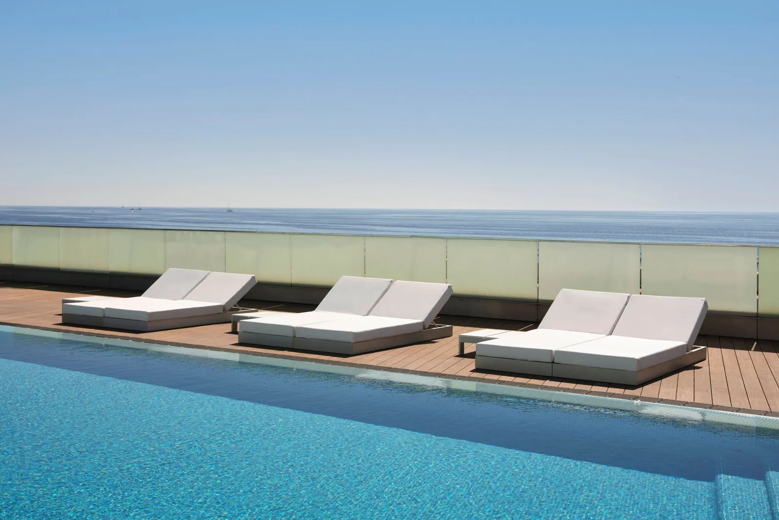 White loungers on the SUN Deck between the infinity pool and the sea