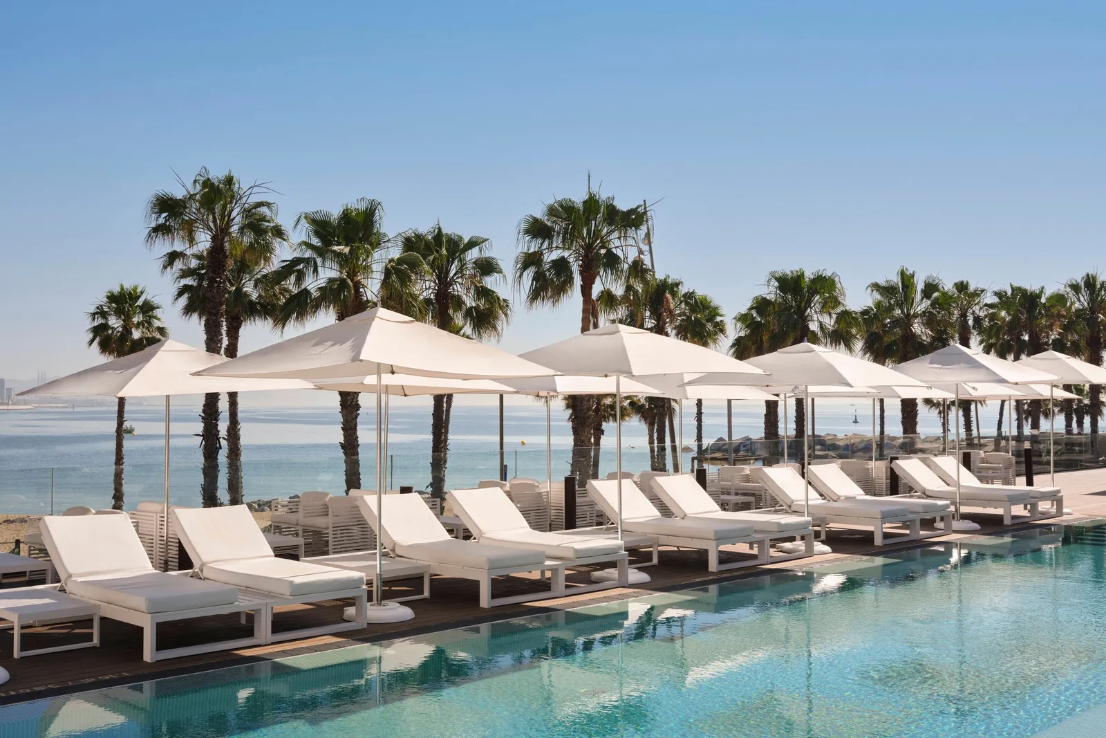 White parasols and palms around the WET Deck pool