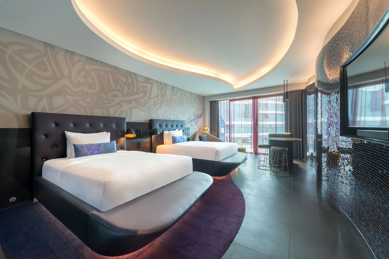 A room with 2 double beds, a purple rug and a yellow armchair