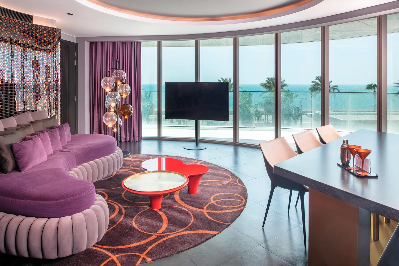 The Fantastic Suite living room with a round purple sofa and a red table