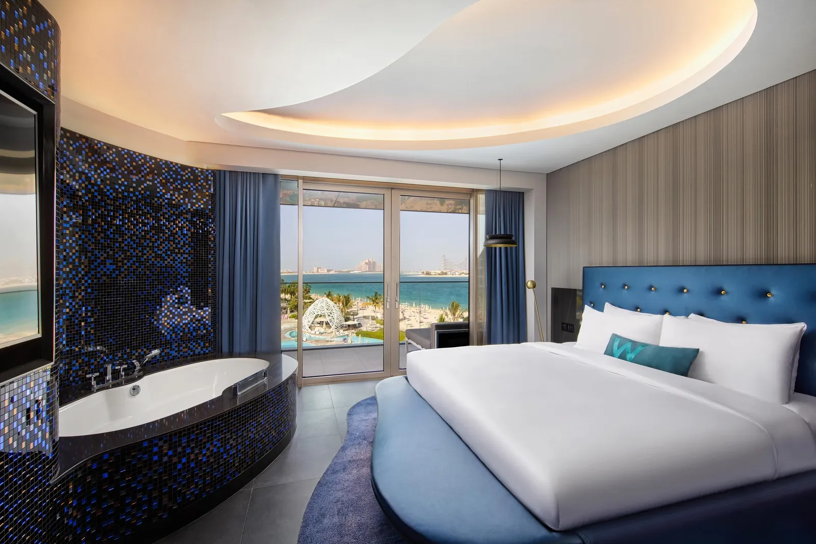 A Mega Suite bedroom with a king bed and the city beyond the glass