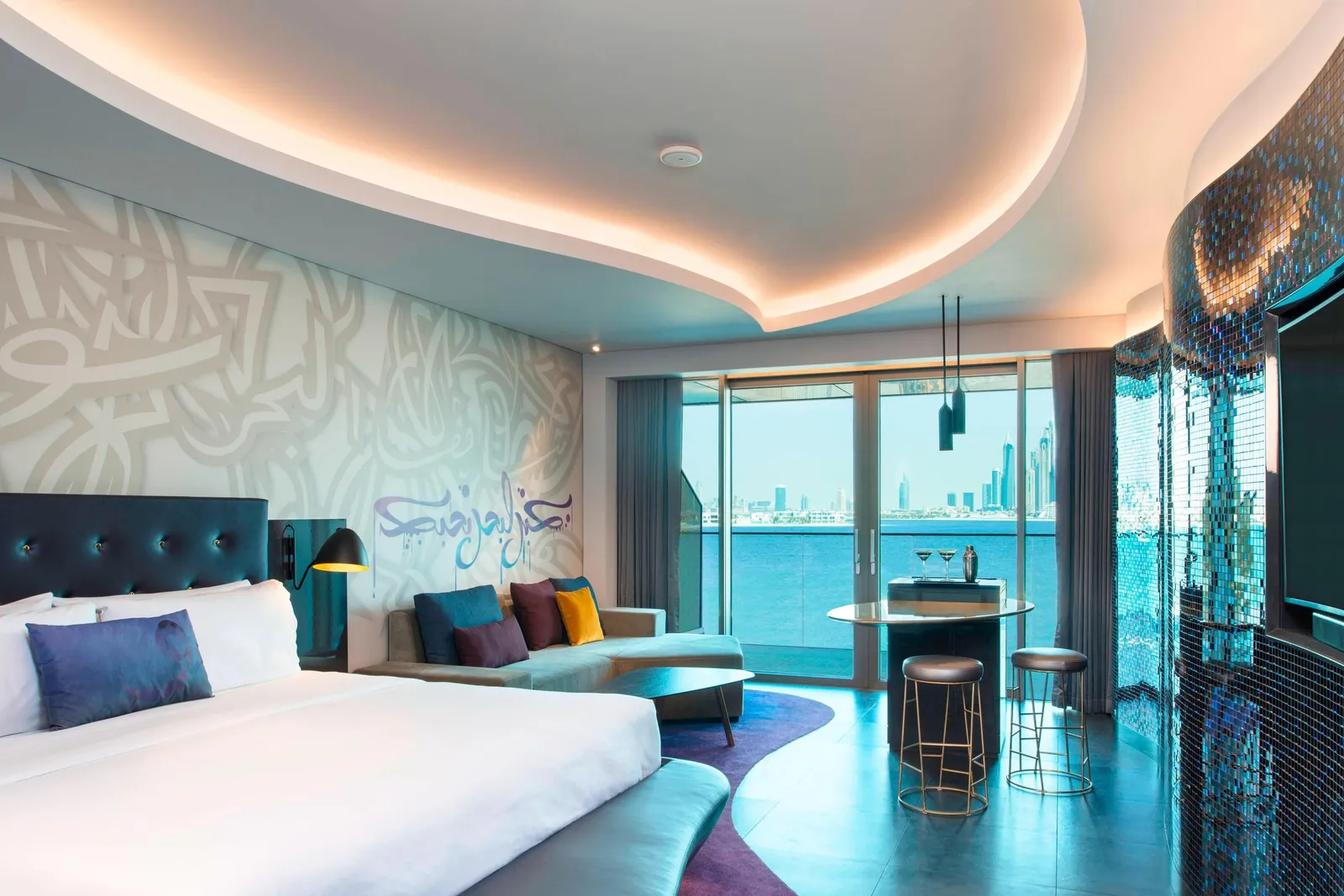 A Spectacular room with the bed, a blue armchair and towers beyond the balcony
