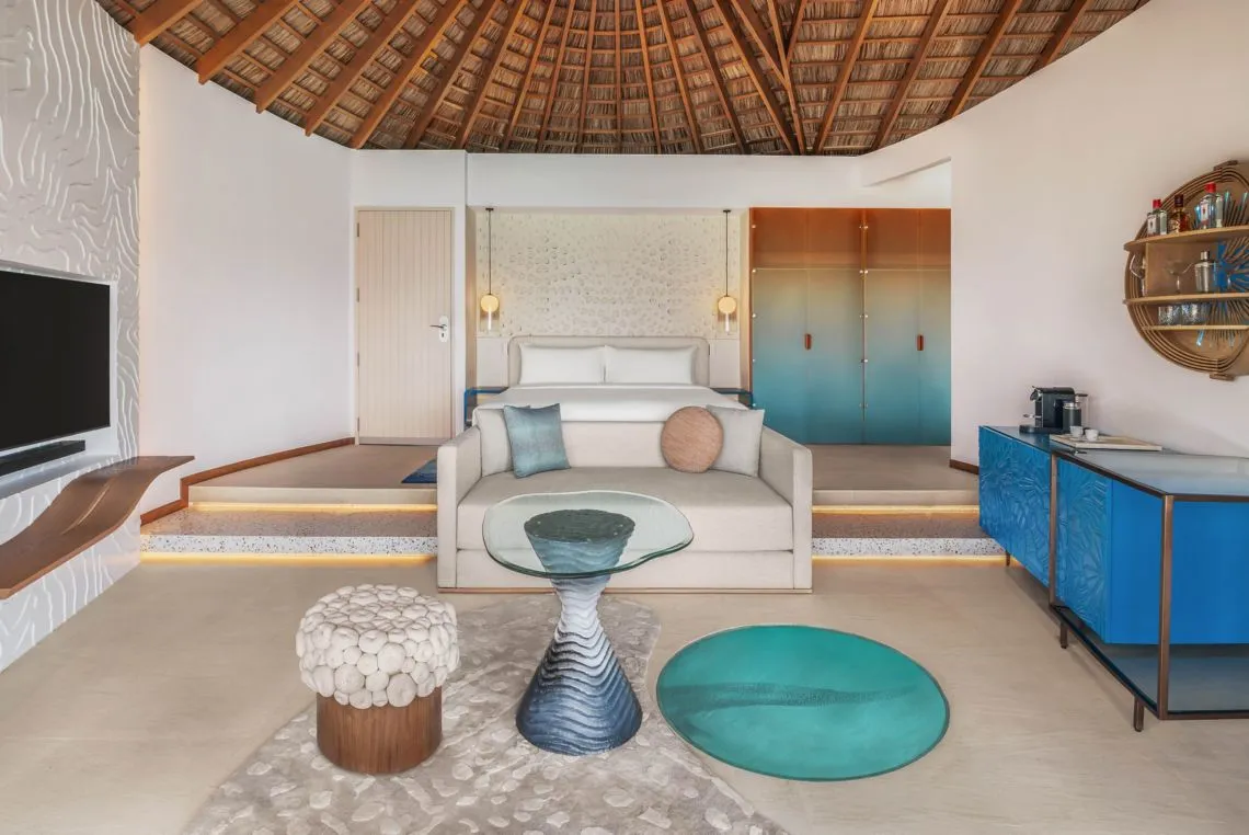 The Superior Overwater bedroom with a raised bed, sofa and floor window