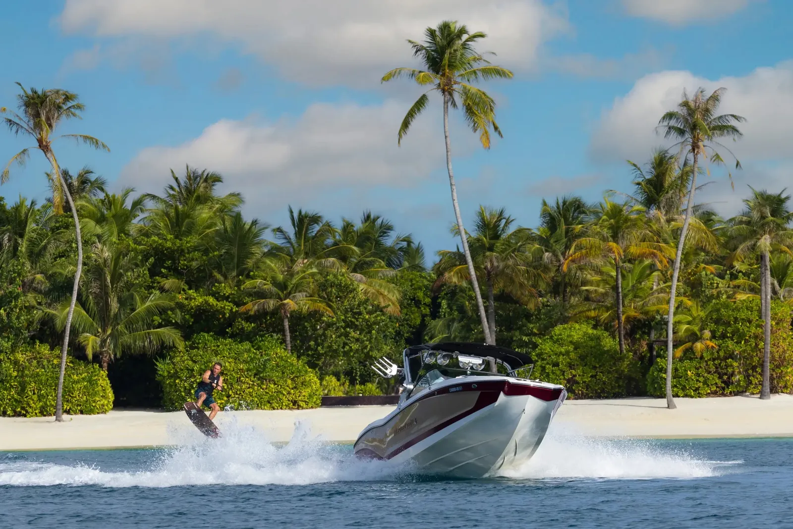 A speedboat racing along the beach, palms behind