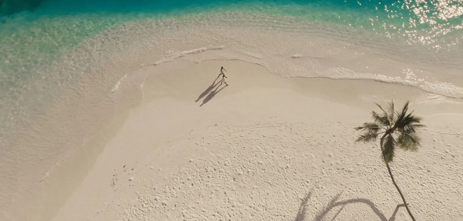 A spit of white sand and a figure walking towards the water