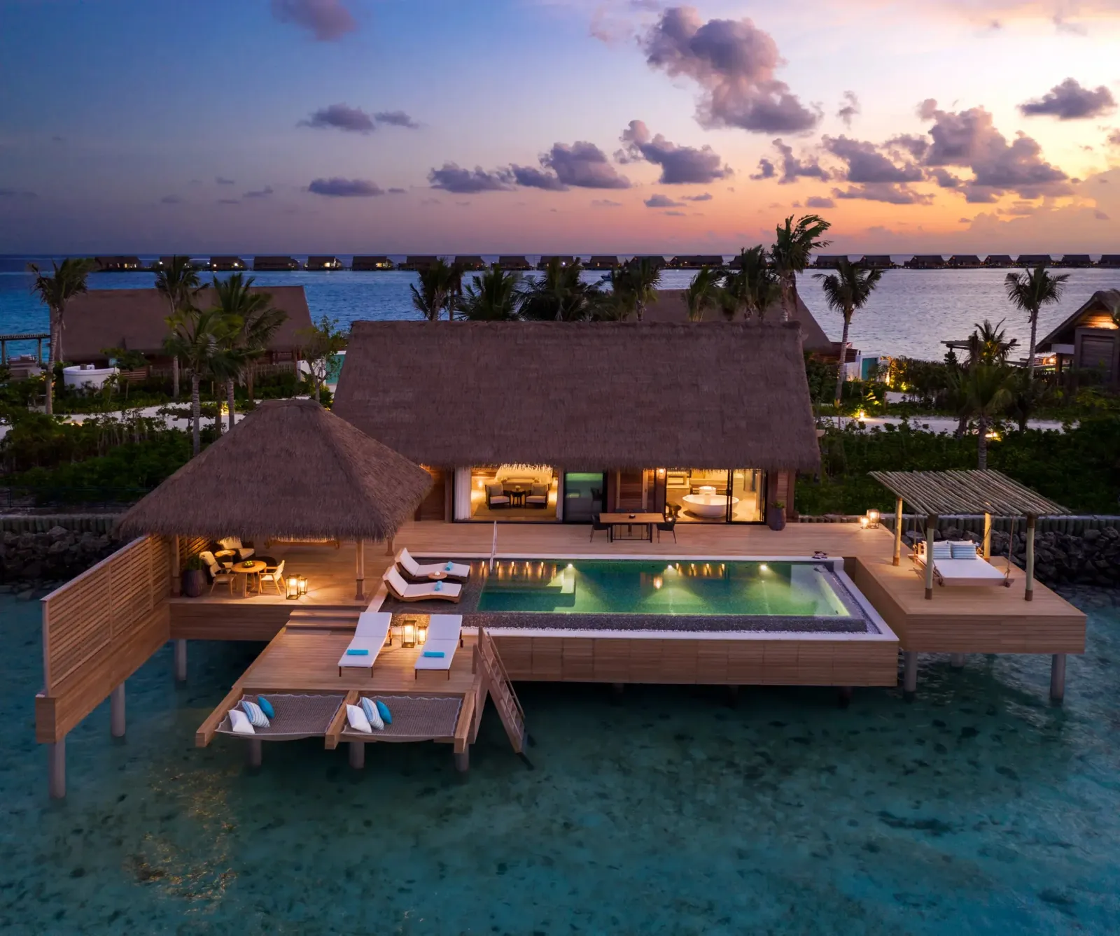 King Reef Villa at dusk, its deck and pool over the water