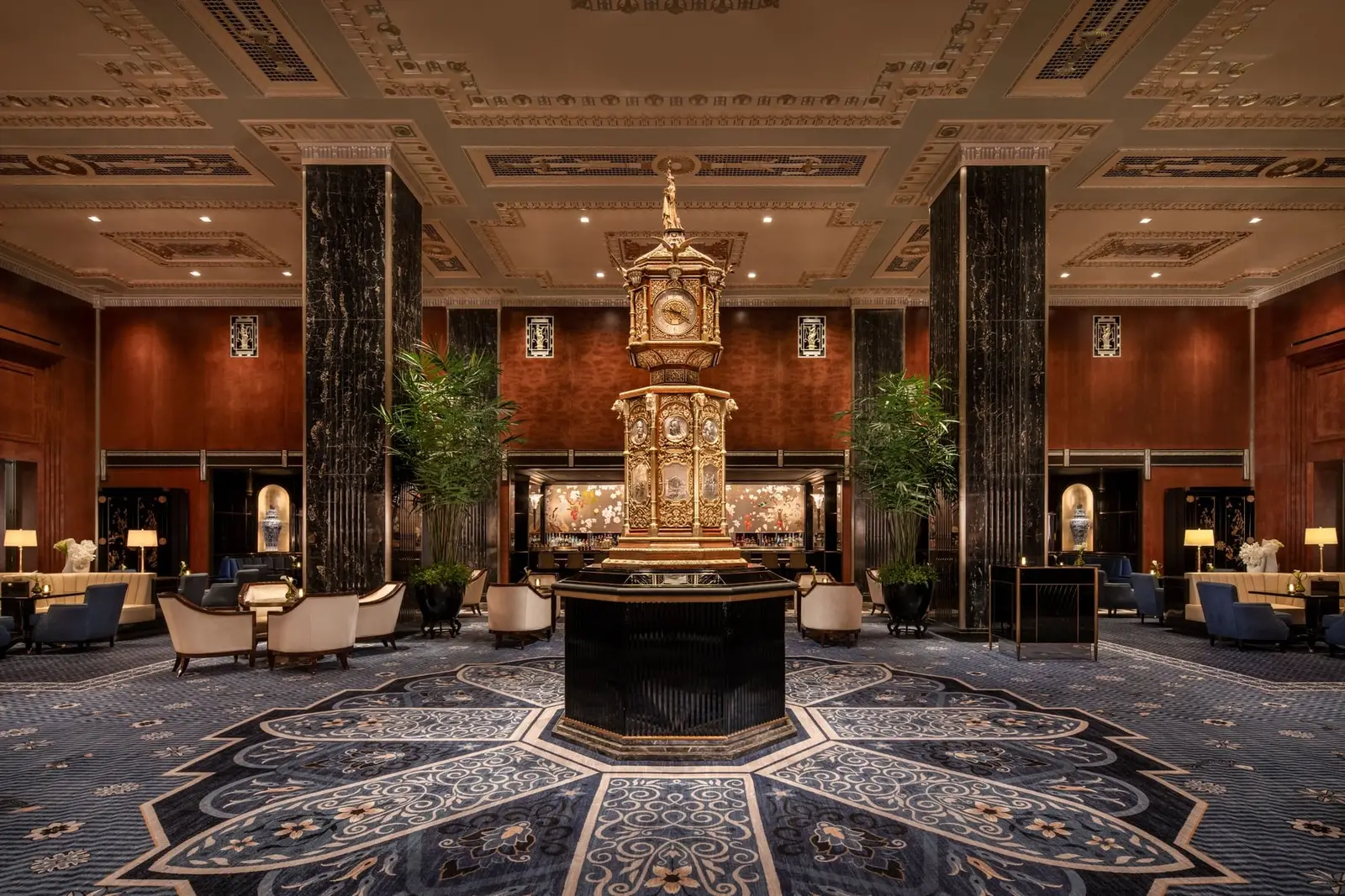 Peacock Alley with the Grand Clock at its centre, the armchairs and the dark columns