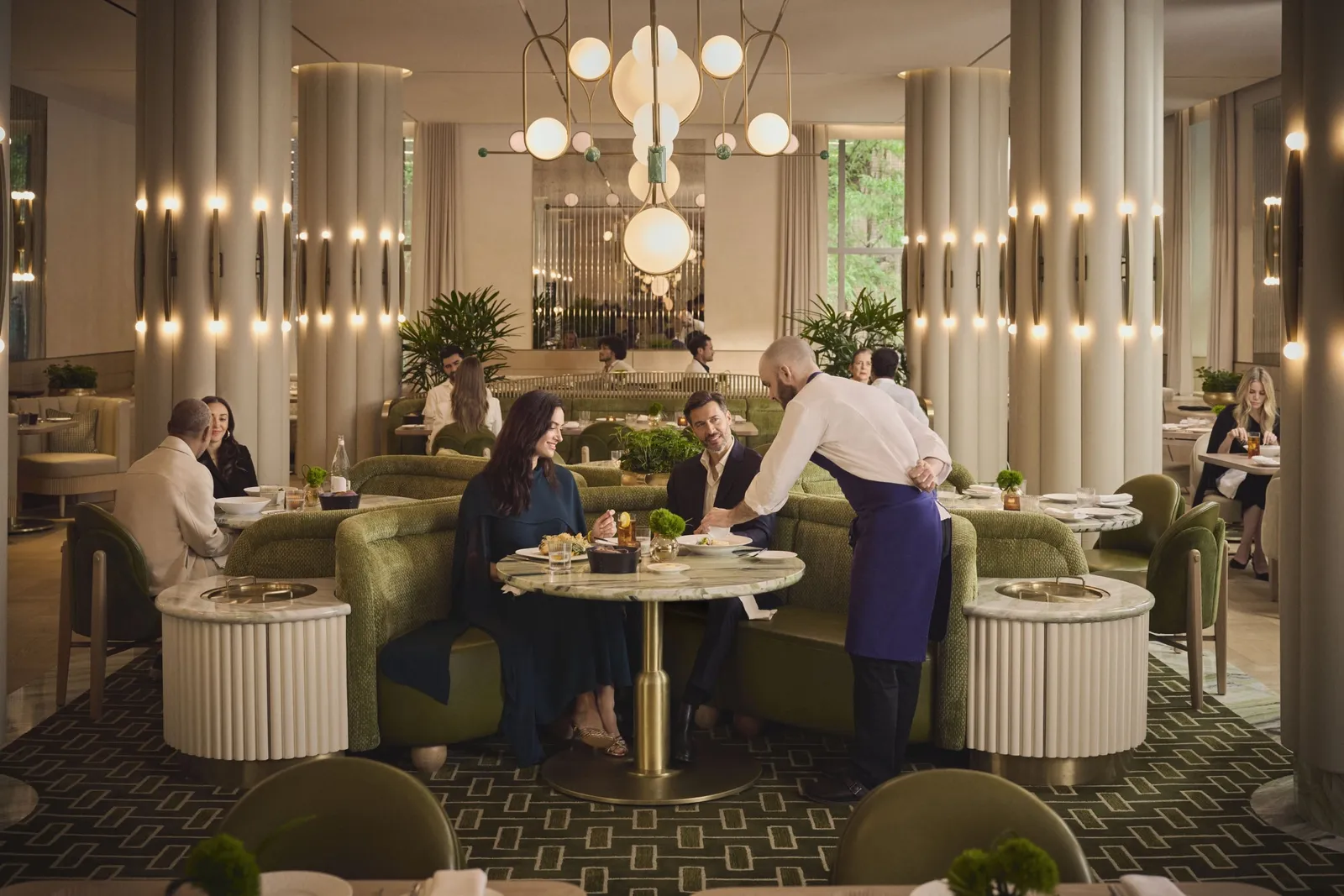 Lex Yard’s upstairs Dining Room, diners at round tables and a waiter between the pale columns