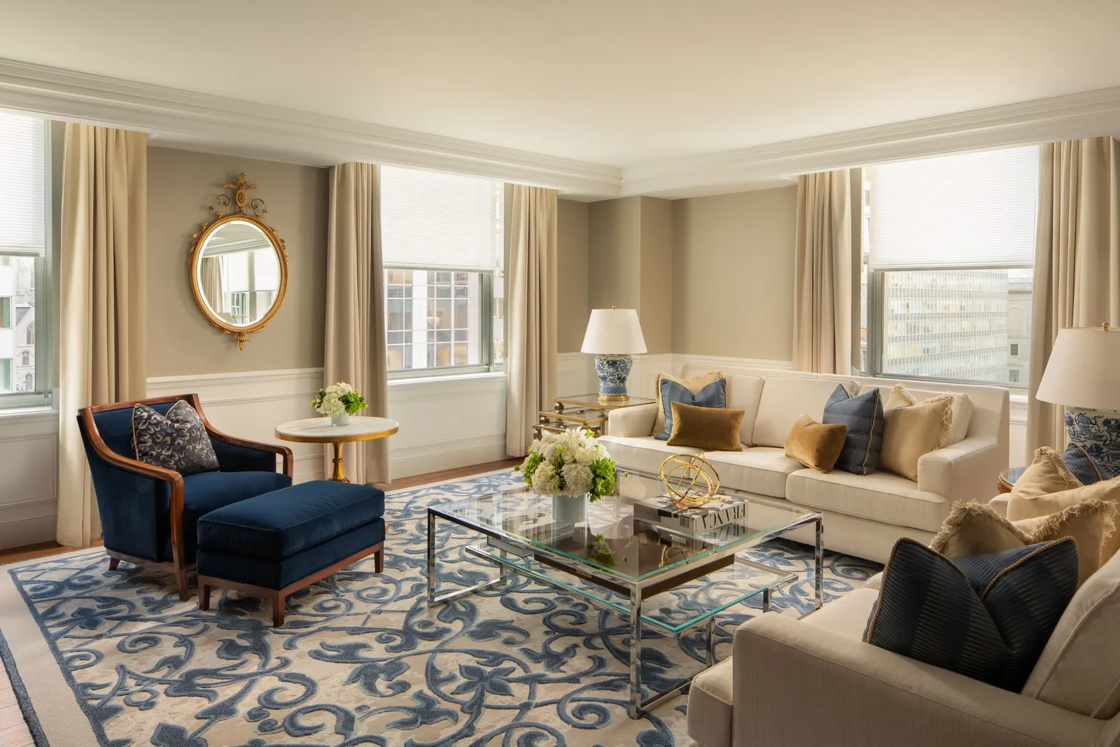 The Empire Suite living room with its round mirror and navy armchairs