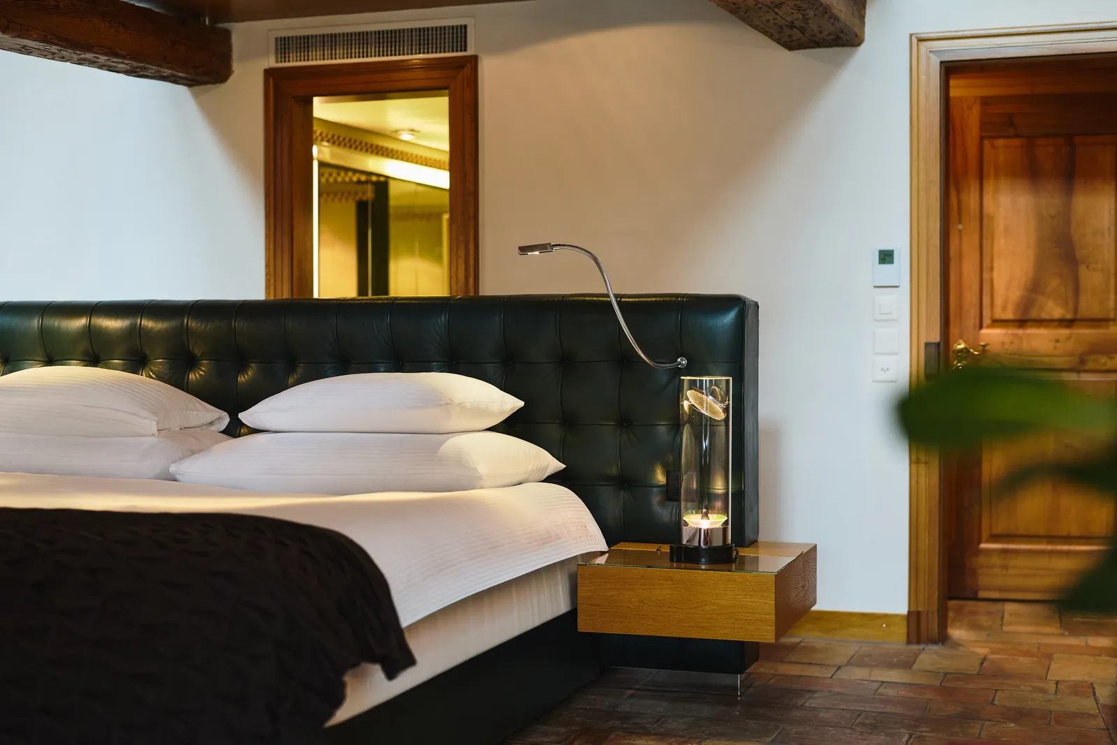 Letto con testiera verde scuro sotto le travi della mansarda