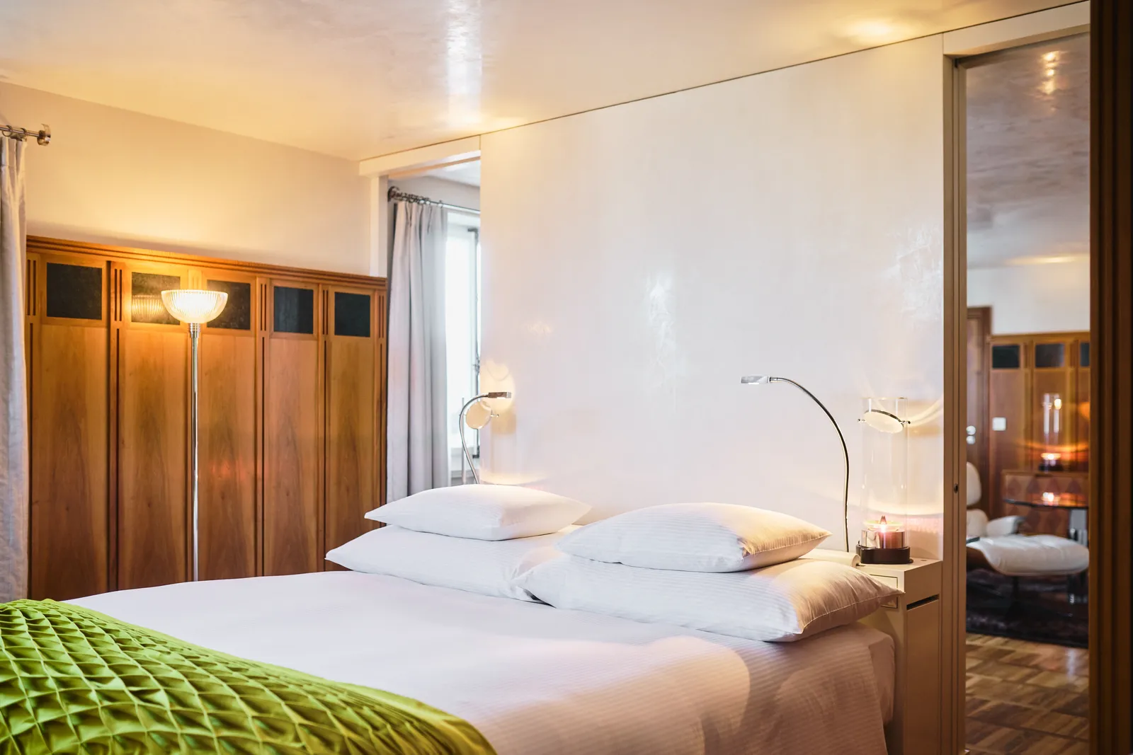 Letto con coperta verde accanto alle finestre della Design Suite