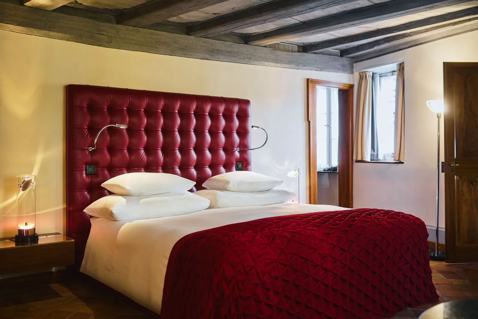 Letto matrimoniale con testiera rossa e soffitto a travi della Family Suite