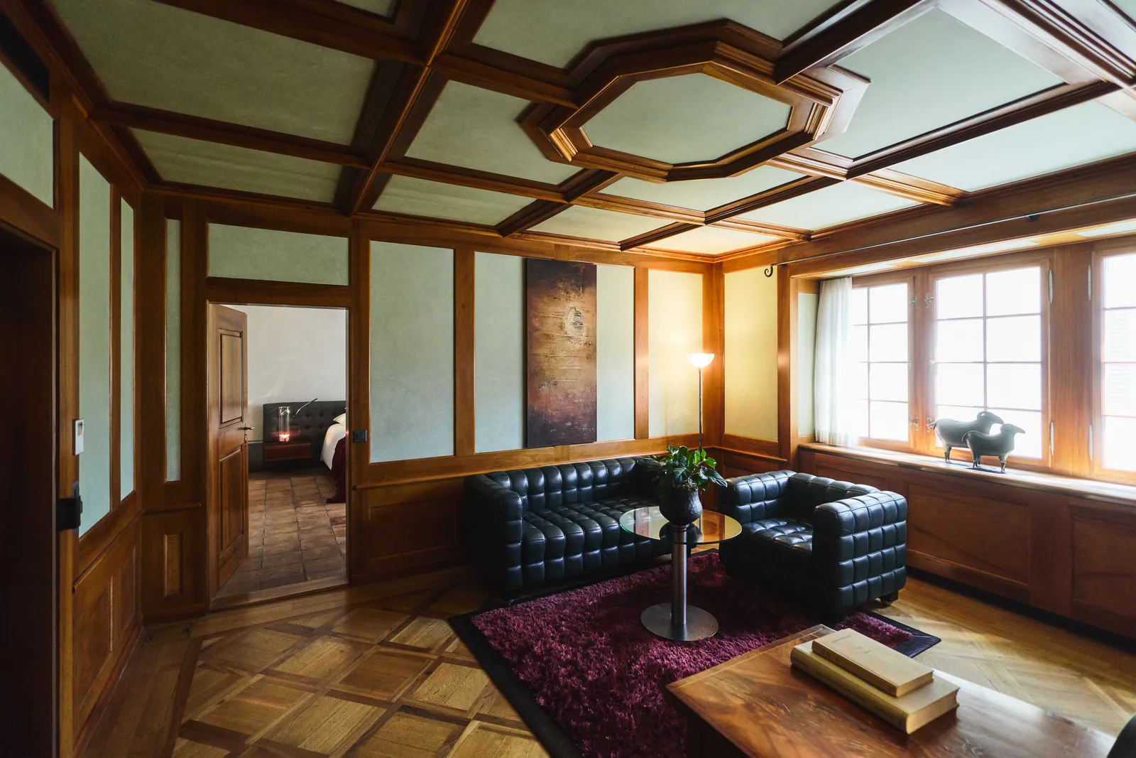 Soggiorno con divani neri, tavolino e soffitto a cassettoni