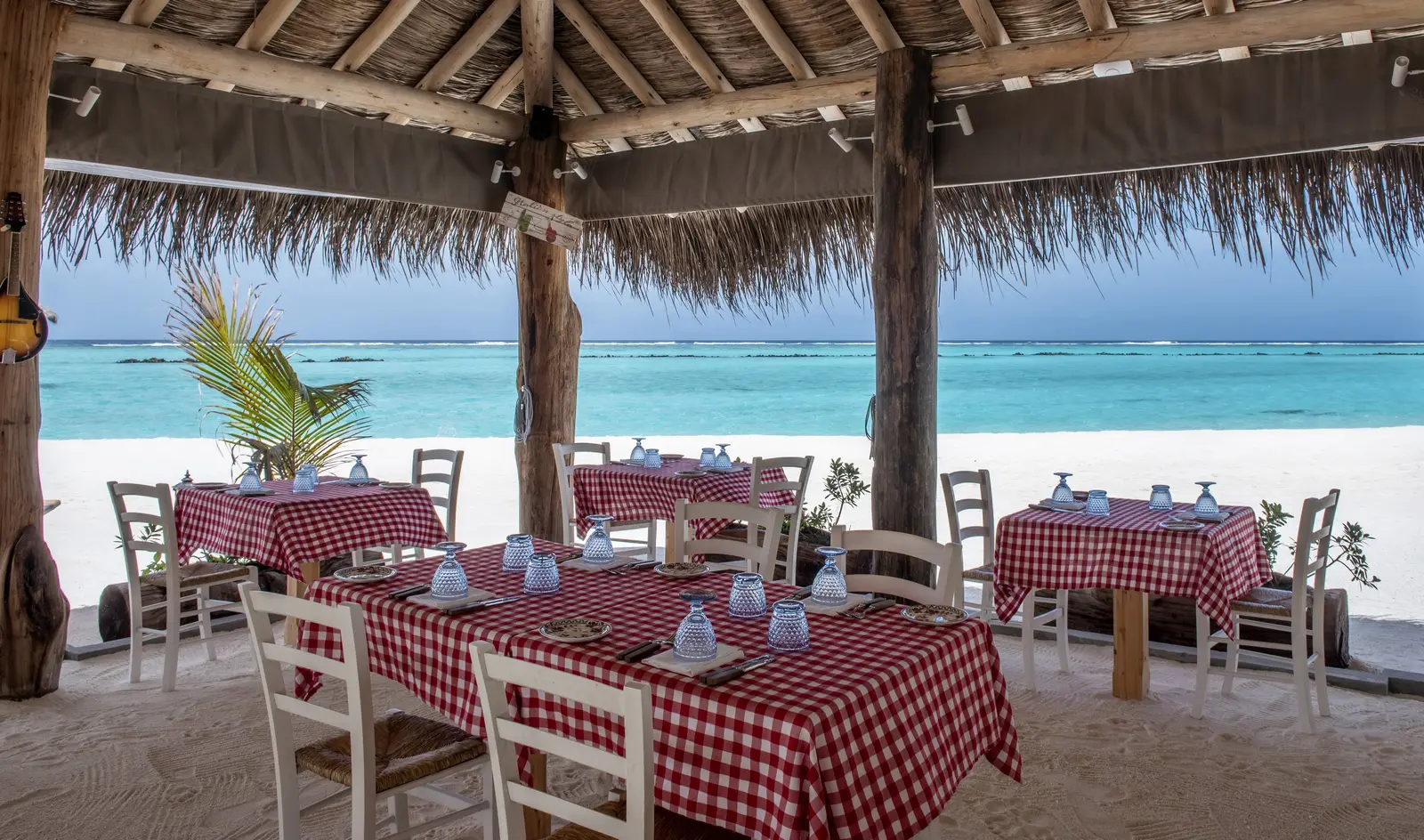 La Pasta on the beach, red-checked tablecloths beneath the thatch
