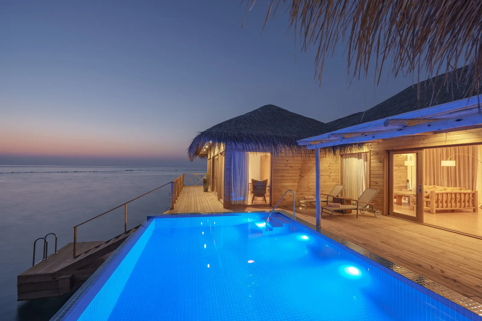 The You & Me Suite at dusk, its lit pool along the deck over the water