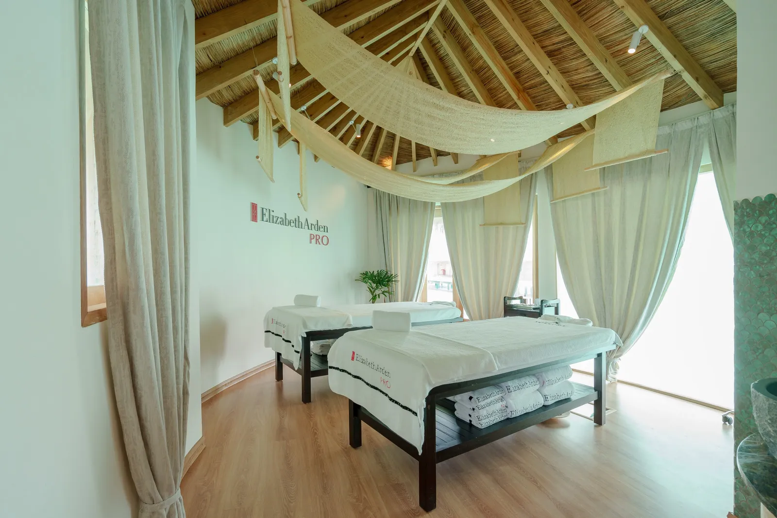 A spa room with 2 massage beds beneath a canvas canopy, the curtains open to the sea