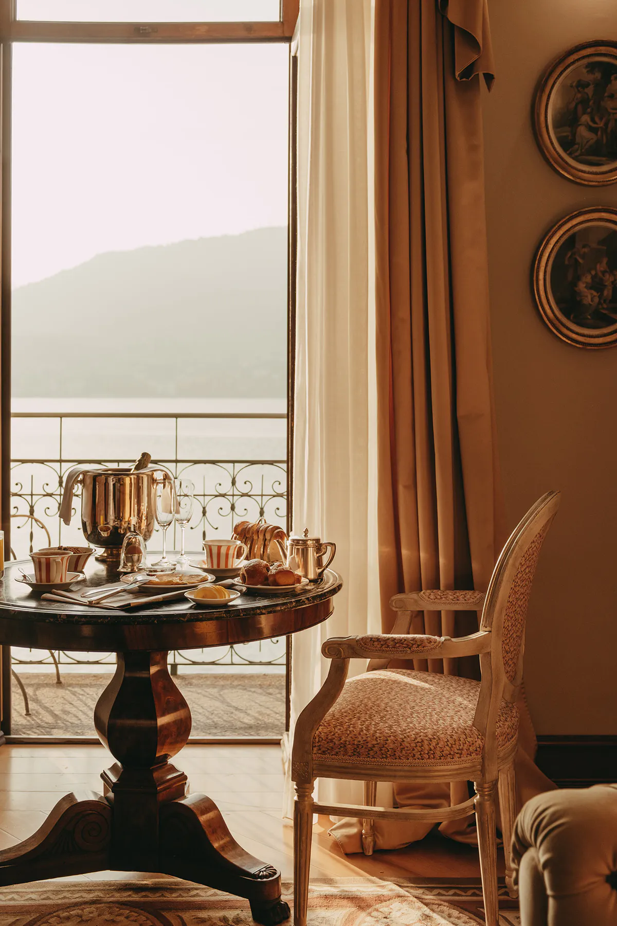 Breakfast table and silver teapot beside a lake-facing window