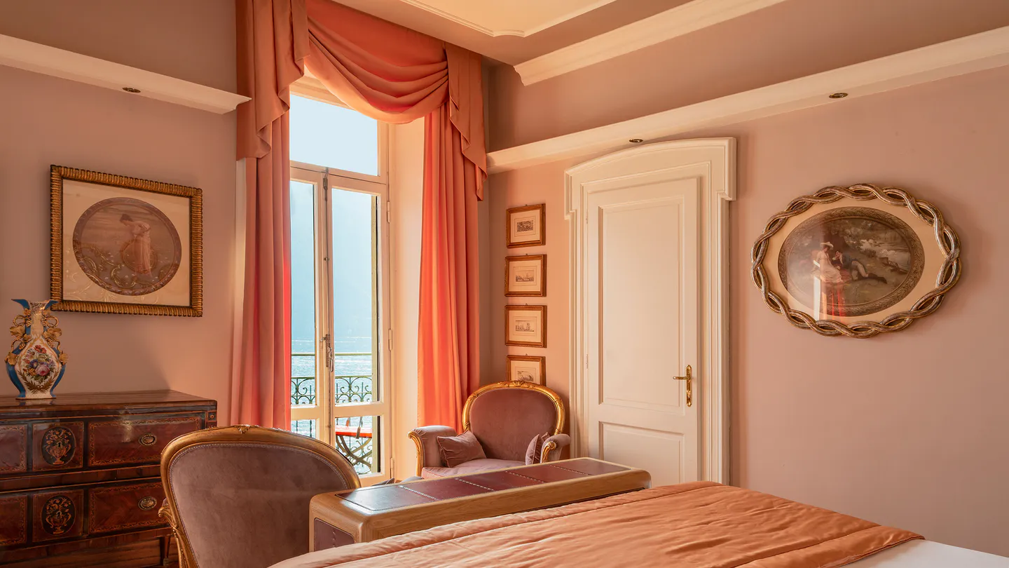 Lake-view Junior Suite with pink curtains and a balcony